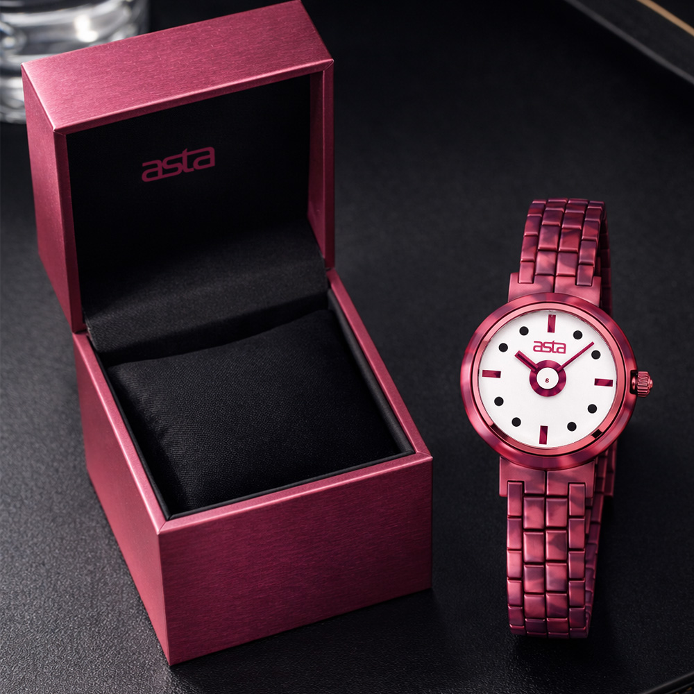 Styled product photo of a asta women's fuchsia acetate bracelet watch featuring a white dial, dot hour markers and bold hands, displayed beside a gift box